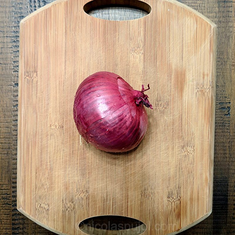 raw red onion on cutting board