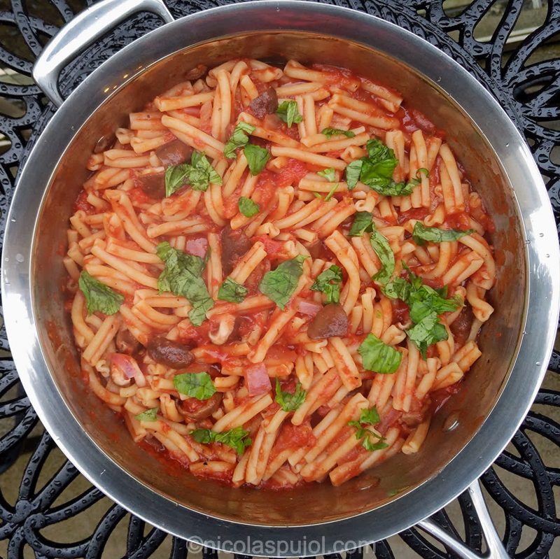 Large pan of vegan pasta in tomato sauce with basil