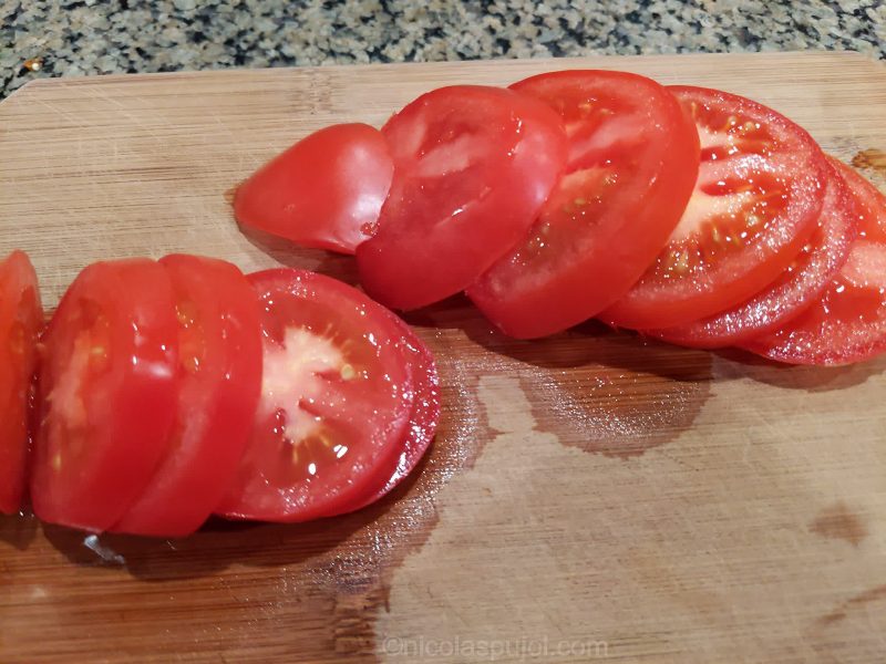 Slicing tomatoes for vegan caprese salad