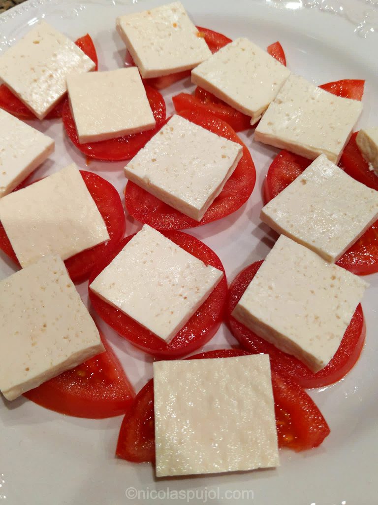 Tofu slices on tomato for vegan caprese
